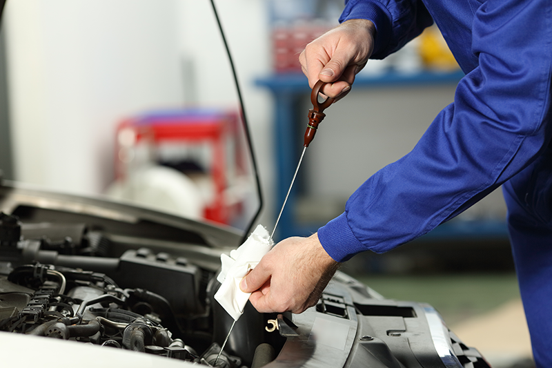 Certified service technician performing an engine oil level check as part of routine maintenance, highlighting professional oil change service and preventative vehicle care.