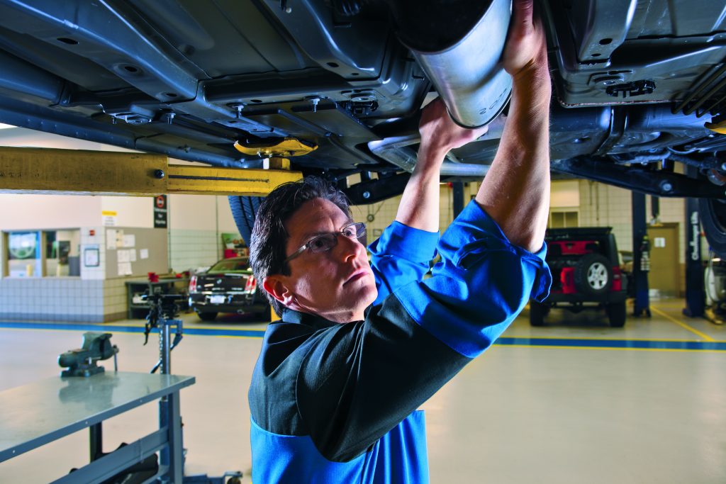 Mechanic performing maintenance under a vehicle.