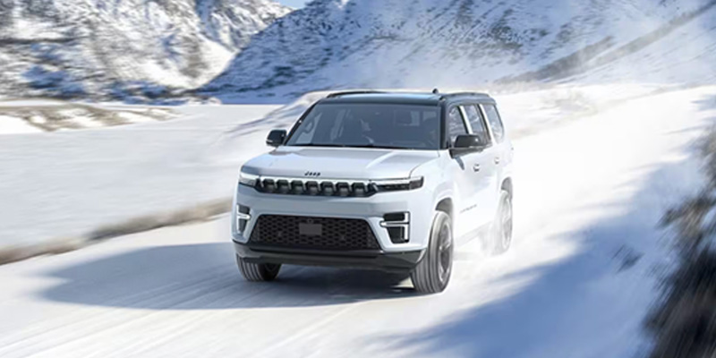 2026 Jeep Grand Cherokee driving through snowy terrain, showcasing its off-road capabilities and rugged design