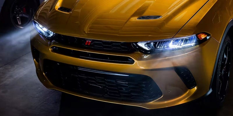 front view of a yellow 2024 dodge hornet with headlights on